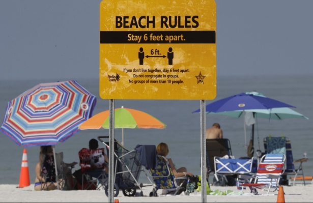 Beachgoers sunbathe near a beach rules sign after Clearwater Beach officially reopened to the public in Clearwater Beach, Fla., on May 4, 2020. (Chris O'Meara/AP Photo)