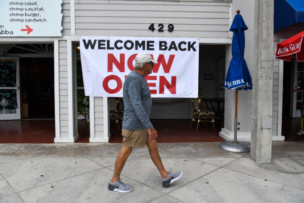 A man walks past a sign reading "Welcome Back, Now Open" on Fort Lauderdale Beach Boulevard in Fort Lauderdale, Fla., on May 18, 2020. (Chandan Khanna/AFP via Getty Images)