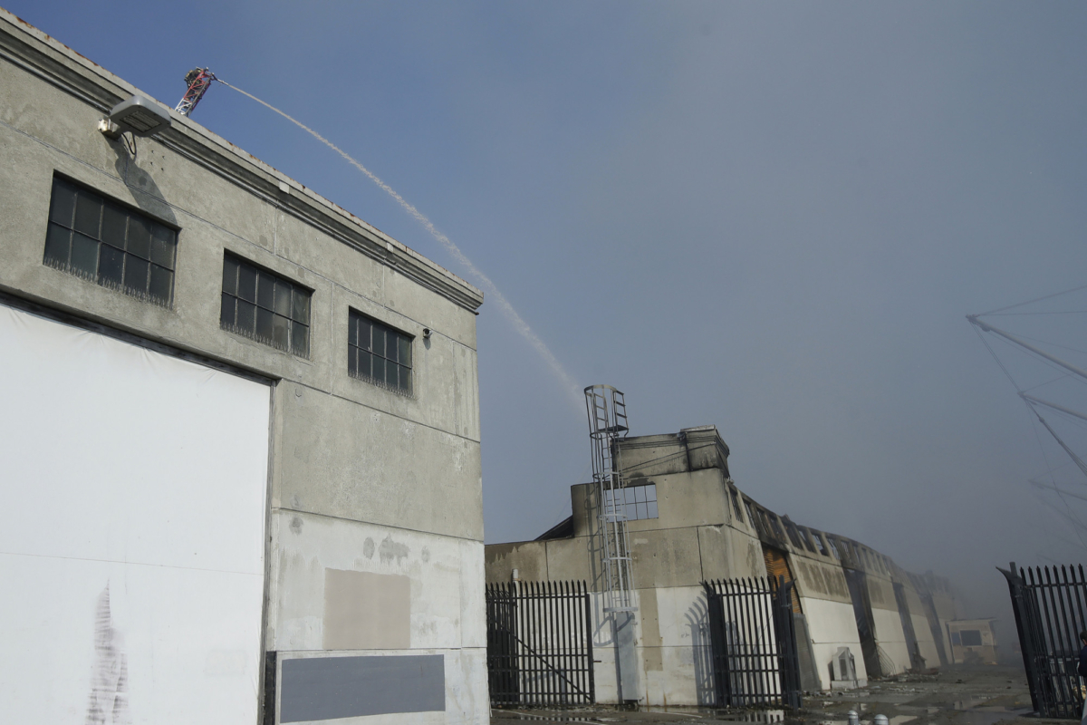 A firefighter sprays into a warehouse after a fire broke out before dawn at Fisherman's Wharf in San Francisco, Saturday, May 23, 2020. (Jeff Chiu/AP photo)