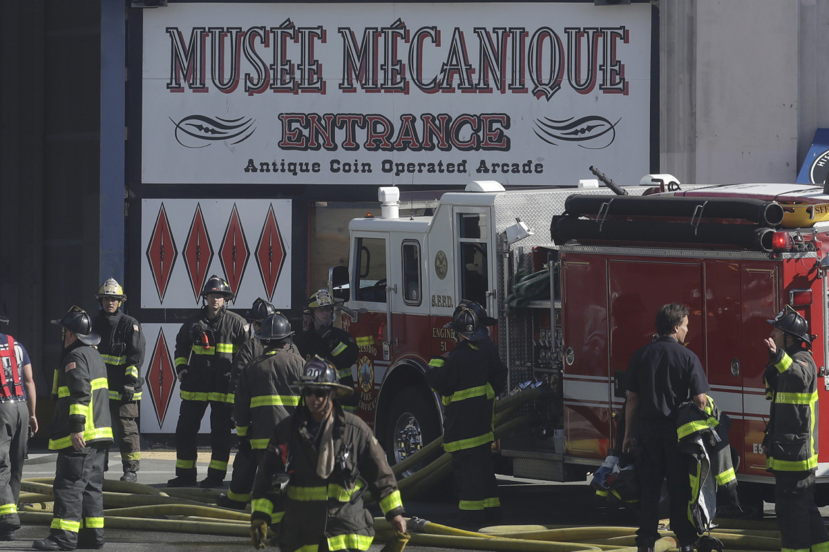 Fire officials work in front of a sign for Musee Mecanique after a fire broke out before dawn at Fisherman's Wharf in San Francisco, Saturday, May 23, 2020. (Jeff Chiu/AP photo)