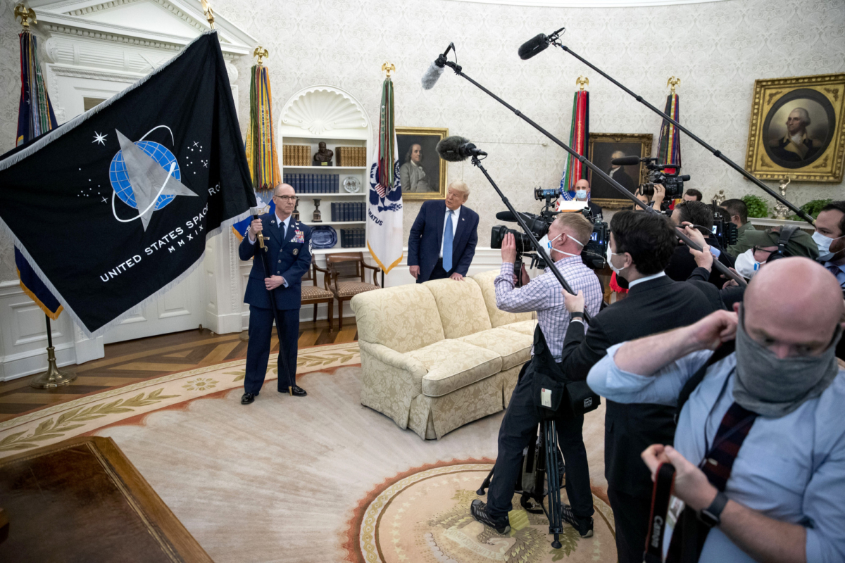 U.S. Air Force Space Command, Chief Master Sgt. Roger Towberman (C), holds the flag as President Donald Trump watches during the presentation of the Space Force Flag in the Oval Office of the White House, on May 15, 2020. (Alex Brandon/AP Photo)