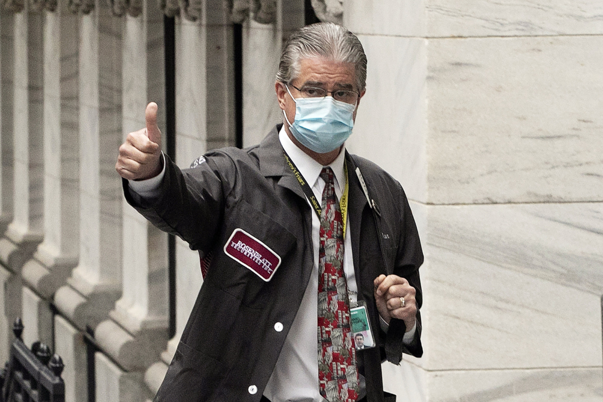Trader Daniel Krieger signals a thumbs-up as he arrives at the New York Stock Exchange where the trading floor reopens, N.Y., on May 26, 2020. (Mark Lennihan/AP Photo)