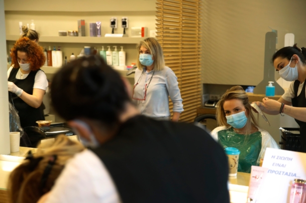 Workers at a hair salon work on customers, all wearing masks to prevent the CCP virus, in Athens on May 4, 2020. (Thanassis Stavrakis/AP Photo)