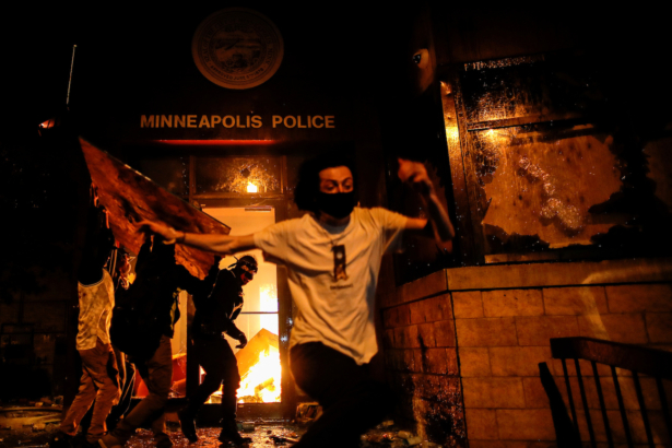 Protesters react as they set fire to the entrance of a police station as demonstrations continue in Minneapolis, Minn., on May 28, 2020. (Carlos Barria/Reuters)