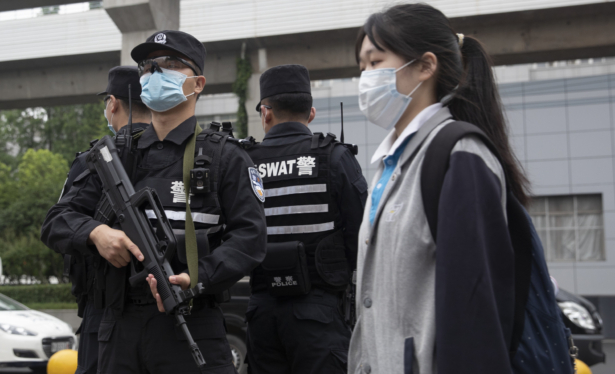 Police officers (L) stand guard at an entrance of a high school as a senior student walks past to enter the premises in Wuhan in China's central Hubei province, China, on May 6, 2020. (STR/AFP via Getty Images)