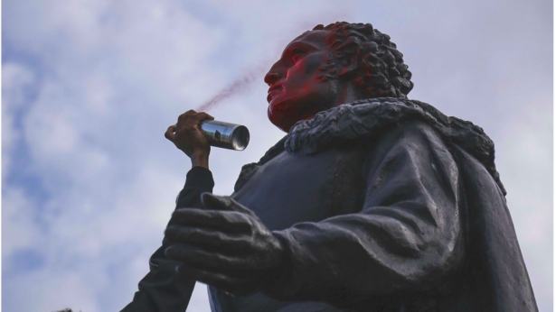 A protester spray paints the face of the statue of Christopher Columbus as the small group of protesters walked through Bayside in Miami, Fla., on June 10, 2020. (Carl Juste/Miami Herald via AP)