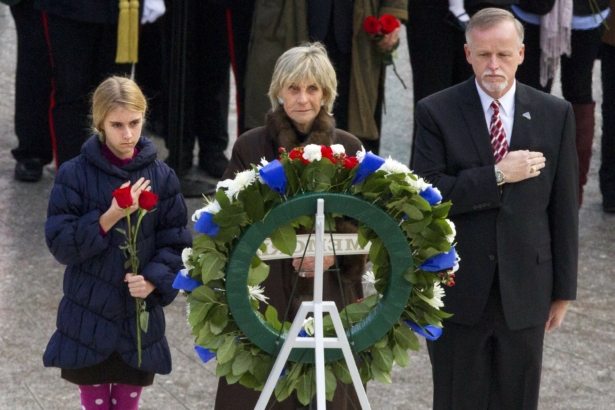 An unidentified girl, left, holds a rose during a wreath-laying ceremony with former Ambassador to Ireland Jean Kennedy Smith, center, and Patrick Hallinan, executive director of Army National Military Cemeteries, at the grave of John F. Kennedy at Arlington National Cemetery, in Arlington, Va., on Nov. 22, 2013. (Jacquelyn Martin/AP Photo)