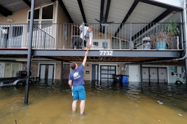 Rudy Horvath hands a piece of wood up to his wife Dawn Horvath, as their home, a boathouse in the West End section of New Orleans, takes on water a from storm surge in Lake Pontchartrain, in advance of Tropical Storm Cristobal, La., on, June 7, 2020. (Gerald Herbert/AP Photo)