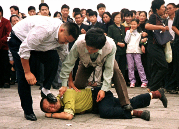 Police detain a Falun Gong protester in Tiananmen Square as a crowd watches in Beijing on Oct. 1, 2000 photo. (Chien-min Chung/AP Photo)
