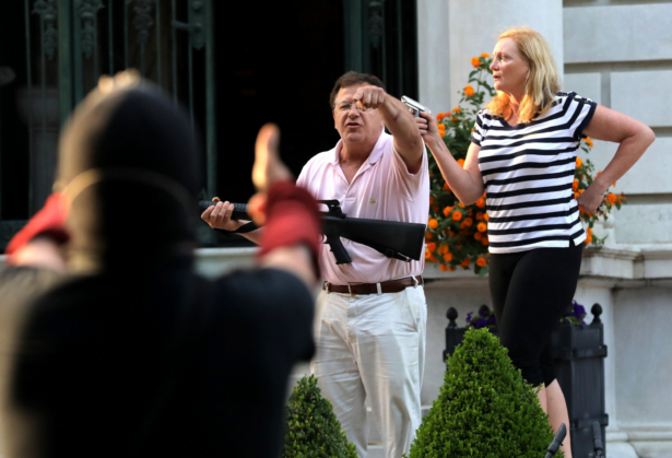 Armed homeowners Mark and Patricia McCloskey stand in front their house along Portland Place confront protesters marching to St. Louis Mayor Lyda Krewson's house in the Central West End of St. Louis, Mo., on June 28, 2020. (Laurie Skrivan/St. Louis Post-Dispatch via AP)