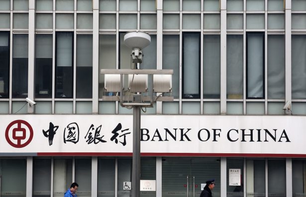 A security official and a man walk past a signboard of Bank of China at its branch in Beijing, on March 26, 2013. (Kim Kyung-Hoon/Reuters)