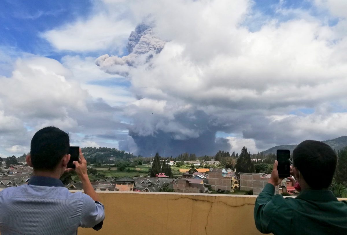 Indonesian men use their mobile phones to take photos as Mount Sinabung spews volcanic materials into the air as it erupts, in Karo, North Sumatra, Indonesia, on Aug. 10, 2020. (Sugeng Nuryono/AP Photo)
