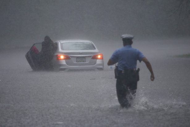 A Philadelphia police officer rushes to help a stranded motorist during Tropical Storm Isaias on Aug. 4, 2020, in Philadelphia. (AP Photo/Matt Slocum)