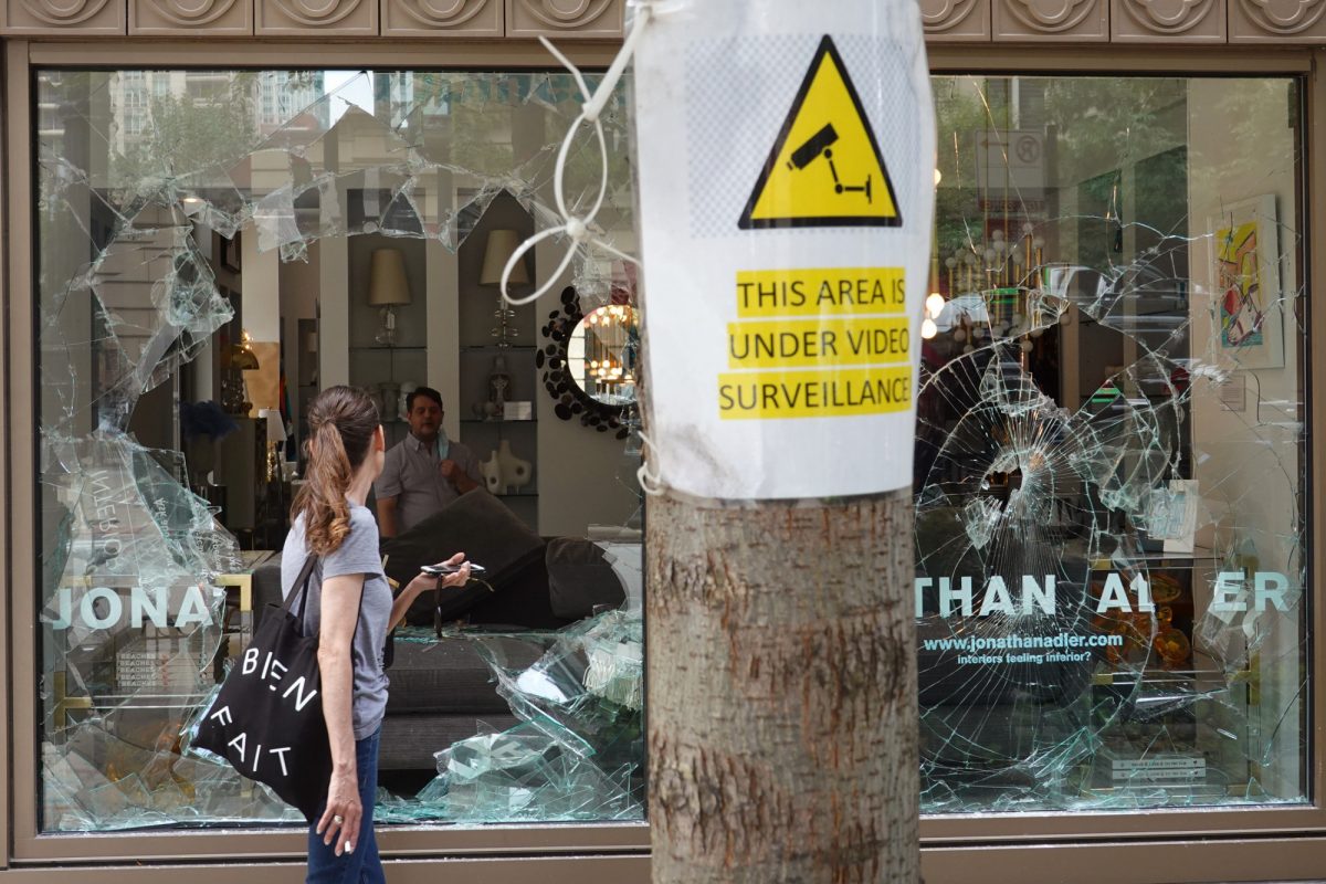 A woman looks through the shattered glass window of the Jonathan Adler interior design store that was looted in Chicago on Aug. 10, 2020. (Scott Olson/Getty Images)