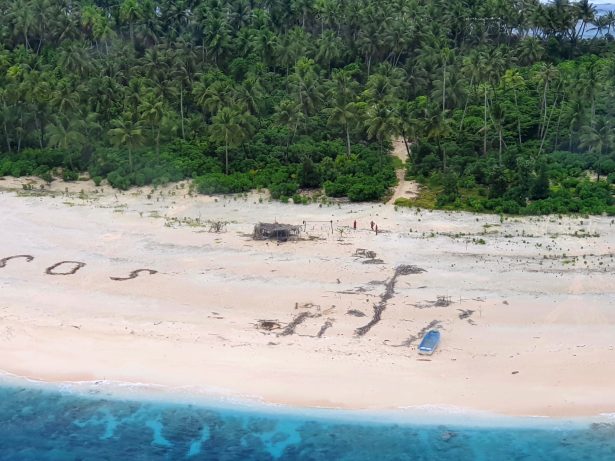 Three men stand the beach on Pikelot Island in the Federated States of Micronesia where they are found safe and healthy after missing for three days, on Aug. 2, 2020. (Australian Defence Force via AP)