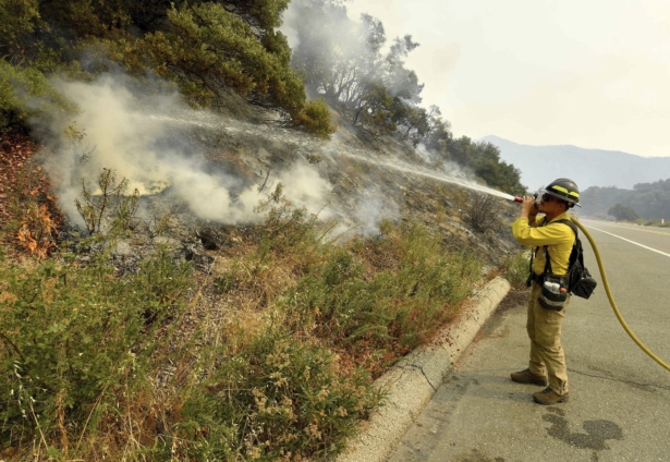 A firefighter puts out a hot spot along Highway 38 northwest of Forrest Falls, Calif., as the El Dorado Fire continues to burn on Sept. 10, 2020.(Will Lester/The Orange County Register/SCNG via AP)