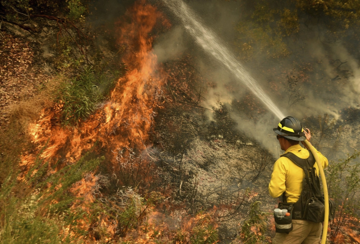 A firefighter puts out a hot spot along Highway 38 northwest of Forrest Falls, Calif., as the El Dorado Fire continues to burn on Sept. 10, 2020. (Will Lester/The Orange County Register/SCNG via AP)