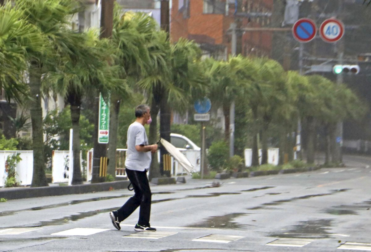 A man makes his way through strong wind with his umbrella broken by the wind in Amami city, Kagoshima prefecture, southwestern Japan on Sept. 6, 2020. (Kyodo News via AP)