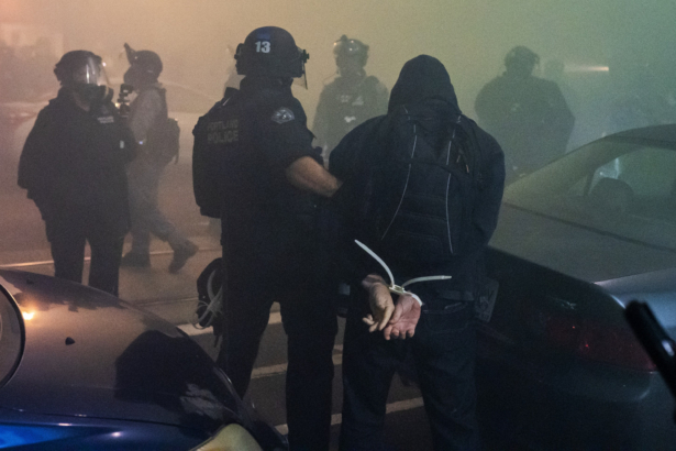 Police arrest a person during the dispersal of an unlawful assembly at the Immigration and Customs Enforcement detention center in Portland, Ore., on Sept. 18, 2020. (Nathan Howard/Getty Images)