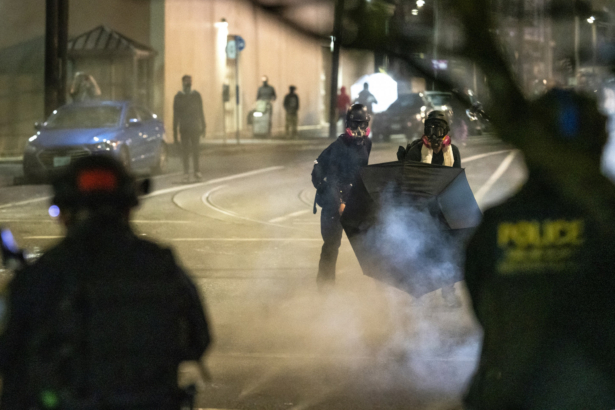 People use umbrellas to block less lethal rounds fired by federal officers during an unlawful assembly at the Immigration and Customs Enforcement detention center in Portland, Ore., on Sept. 18, 2020. (Nathan Howard/Getty Images)