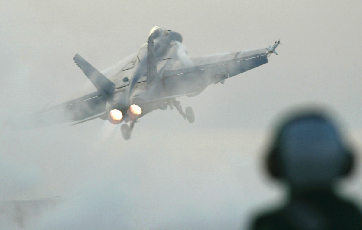 A flight deck handler watches as an F/A 18E Super Hornet is launched from the USS Nimitz in the Prsian Gulf on April 11, 2003. (Richard Vogel/AP Photo)