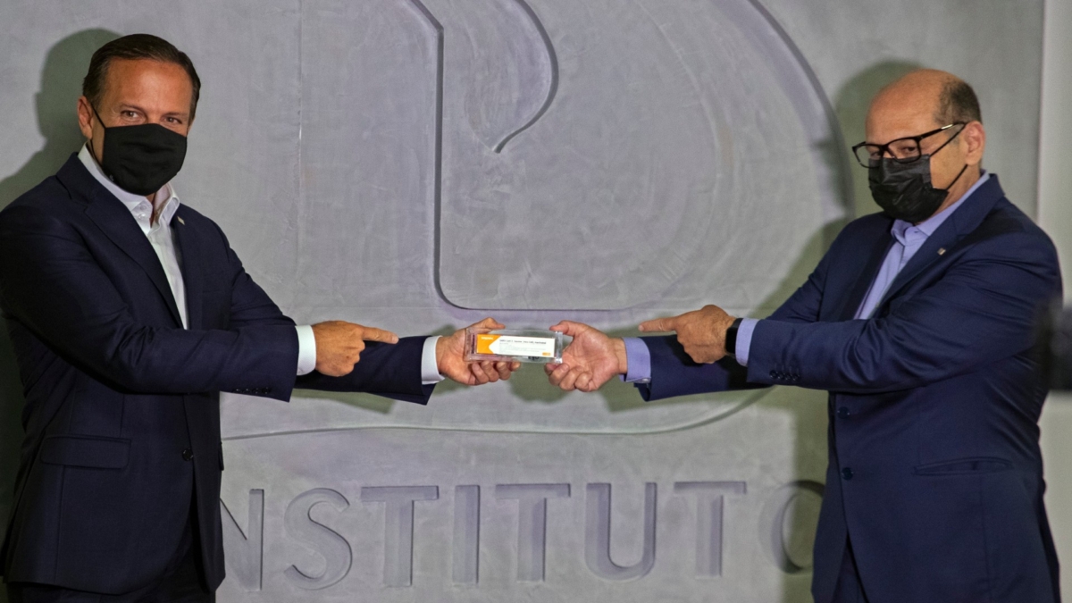 Sao Paulo Governor Joao Doria (L) and Butantan Institute Director Dimas Covas (R) hold up a box of an experimental COVID-19 vaccine during a press conference in Sao Paulo, Brazil, on Nov. 9, 2020. (Andre Penner/AP Photo)