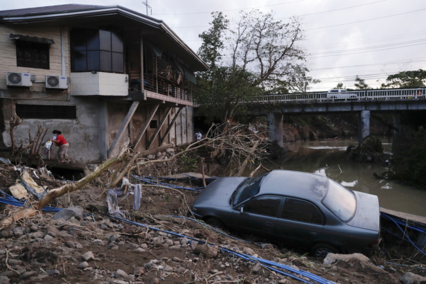 A woman walks past a car that was swept by floodwaters caused by Typhoon Goni in Batangas city, Batangas province, south of Manila, Philippines on Nov. 2, 2020. (Aaron Favila/AP Photo)