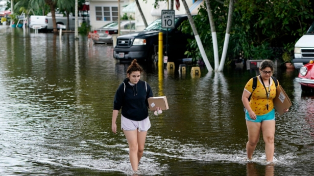 Victoria Rodriguez (L) and Angela Mojica (R) walk on a flooded street in the Driftwood Acres Mobile Home Park, in the aftermath of Tropical Storm Eta, in Davie, Fla., on Nov. 10, 2020. (Lynne Sladky/AP Photo)