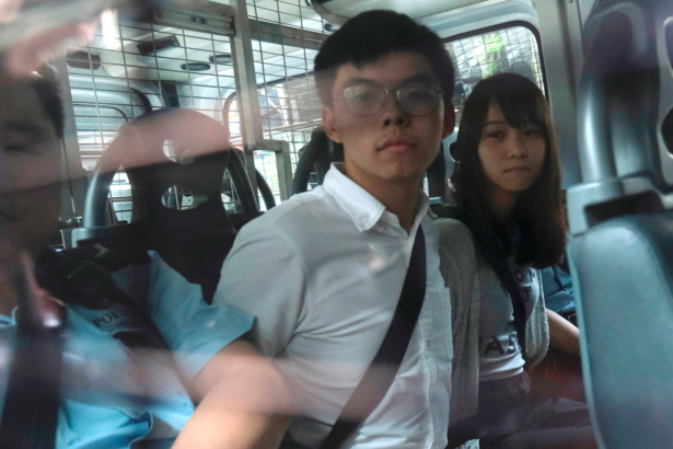 Pro-democracy activists Joshua Wong and Agnes Chow arrive at the Eastern Court by police van after being arrested on suspicion for organising illegal protests, in Hong Kong