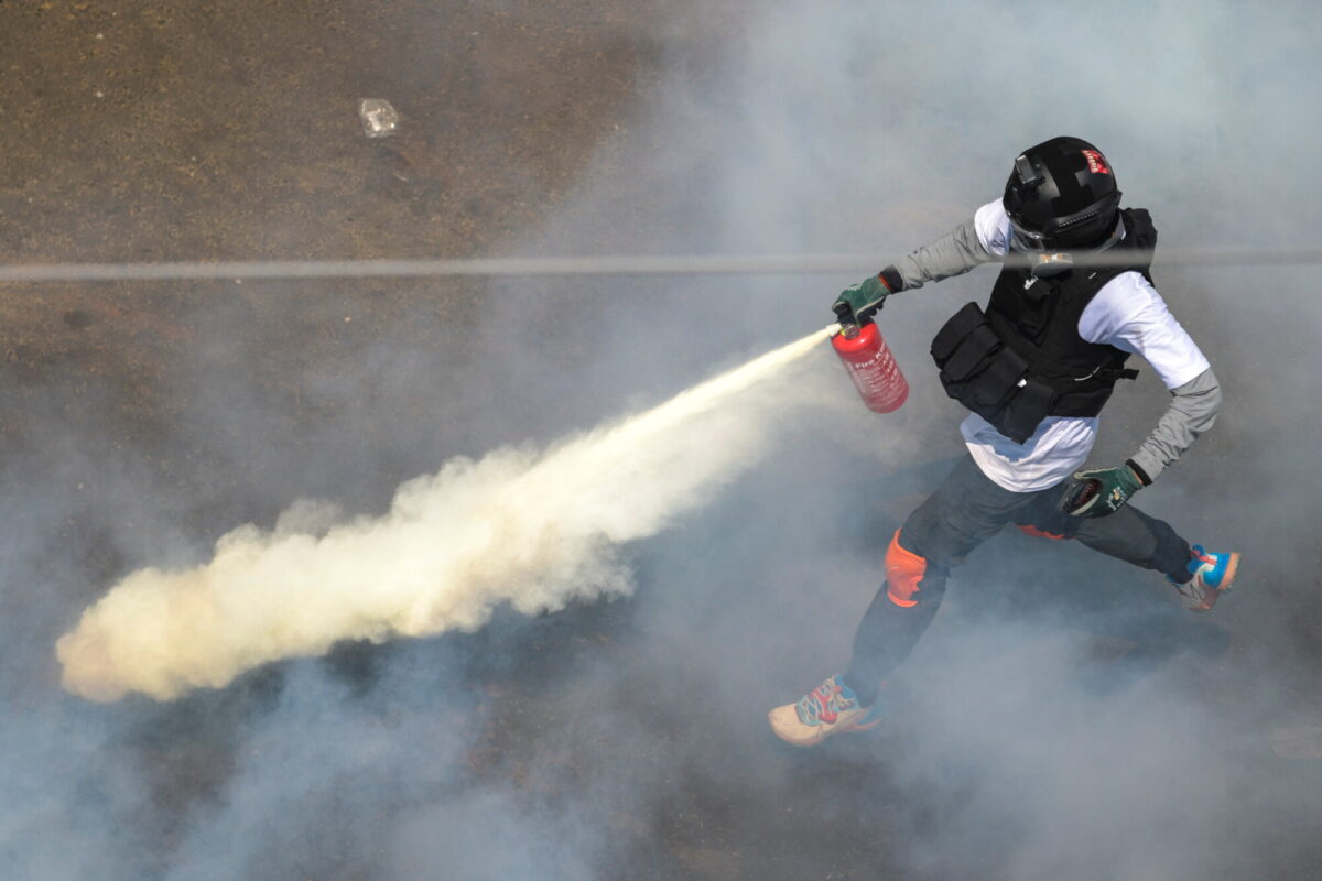 A protester sprays a fire extinguisher as demonstrators clash with riot police officers during a protest against the military coup in Yangon, Burma, on Feb. 28, 2021. (Stringer/Reuters)