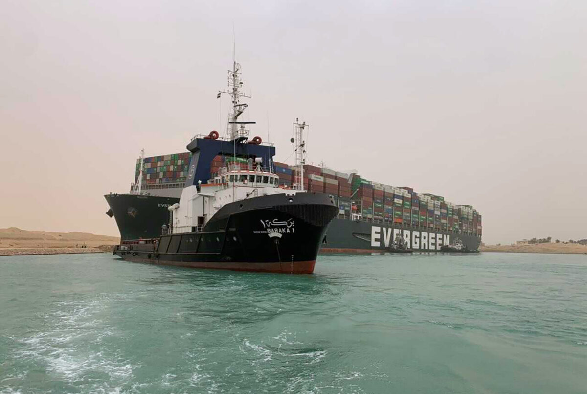 A boat navigates in front of a massive cargo ship, named the Ever Given, in Egypt’s Suez Canal, on March 24, 2021. (Suez Canal Authority via AP)