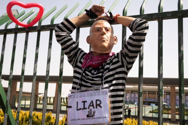 An activist protester wears a mask representing Prime Minister Benjamin Netanyahu, as lawmakers are sworn in following the country's fourth election in two years, in Jerusalem, Israel, on April 6, 2021. (Maya Alleruzzo/AP Photo)