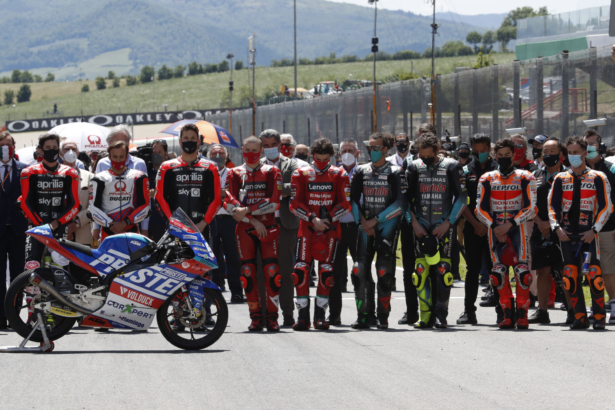 Teammates of 19-year-old Swiss rider Jason Dupasquier and riders from other teams stand near his motorbike as they pay a minute of silence in his memory prior to the start of the MotoGP Grand Prix of Italy at the Mugello circuit, in Scarperia, Italy, on May 30, 2021. (Antonio Calanni/AP Photo)