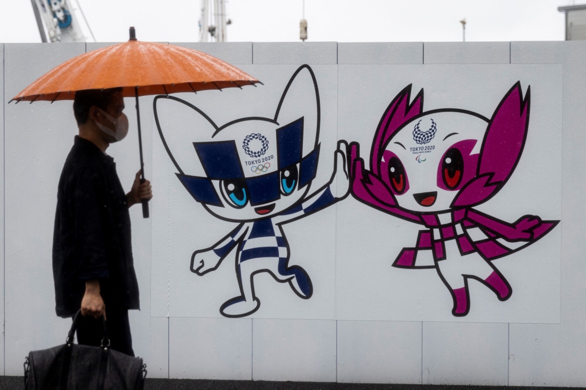 A pedestrian walks past a Tokyo 2020 Olympic and Paralympic Games decoration board bearing illustrations of Games mascots Miraitowa (L) and Someity (R) in Tokyo, Japan, on May 27, 2021. (Behrouz Mehri/AFP via Getty Images)