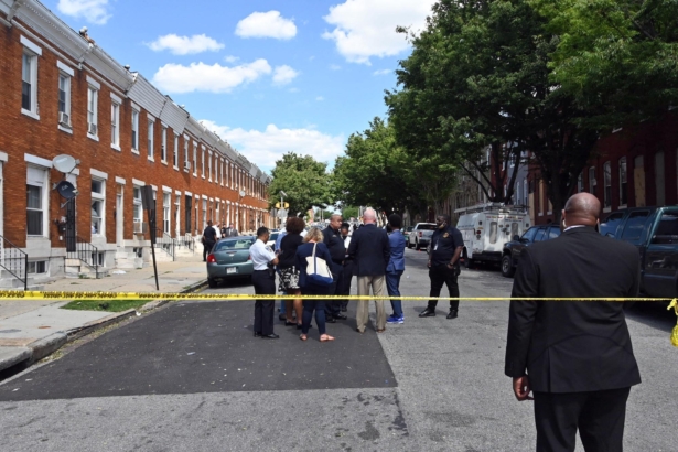 Baltimore Police Commissioner Michael Harrison, center, Baltimore Mayor Brandon Scott, second from right, confer at the scene of a deadly shooting in Baltimore, Maryland on June 16, 2021. (Kim Hairston/The Baltimore Sun via AP)