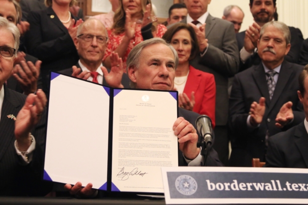 Texas Governor Greg Abbott shows off a bill he signed during a press conference on the border wall at the state capitol in Austin, Texas, on June 16, 2021. (Mei Zhong/The Epoch Times)