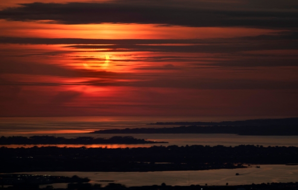 The sun rises partially eclipsed June 10, 2021 in this view taken from behind a window (hence the doubling effect) of Summit One Vanderbilt, a high rise in New York City, on June 10, 2021. (Stan Honda/AFP via Getty Images)