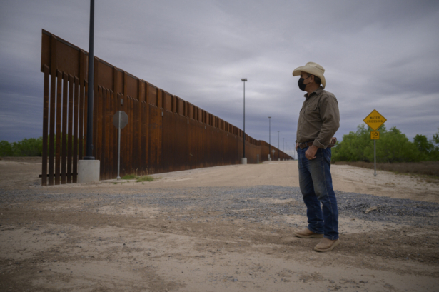 A person stands before a portion of the unfinished border wall near the southern border city of Roma, Texas, on March 28, 2021. (Ed Jones/AFP via Getty Images)