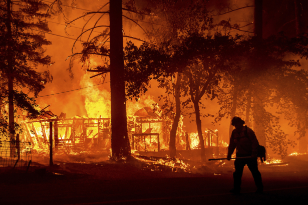 A firefighter passes a burning home