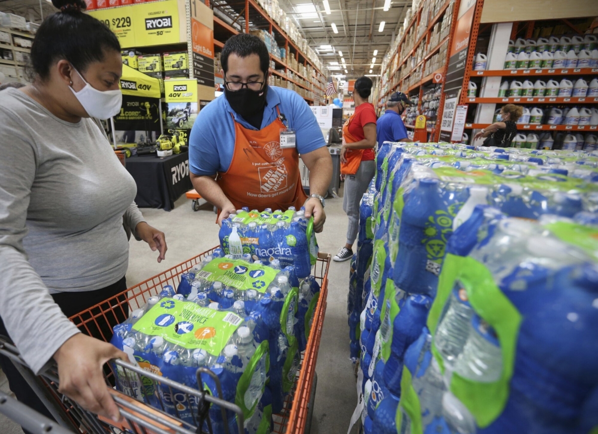 Home Depot department supervisor, Arnaldo Gonzalez, loads water bottles into Elena Arvalo's shopping cart as shoppers prepare for possible effects of tropical storm Elsa in Miami, Fla., on July 3, 2021. (Al Diaz/Miami Herald via AP)