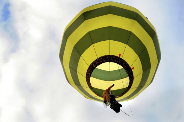 In a harness he created, Brian Boland, of Post Mills, Vt., takes off attached to a hot-air balloon with a passenger above Westshire Elementary School in West Fairlee, Vt., on Feb. 26, 2013. (Jennifer Hauck/The Valley News via AP)