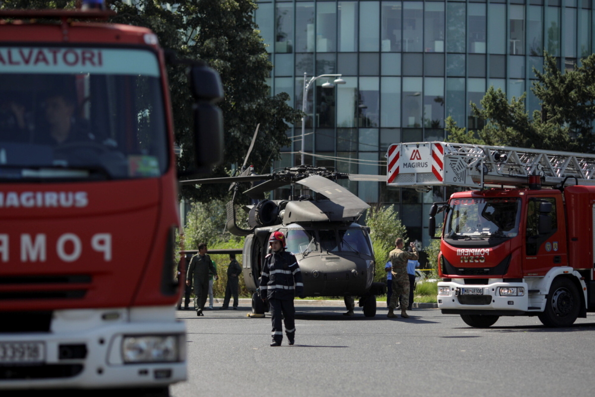 Romanian firefighters are seen near a military Black Hawk helicopter that made an emergency landing in central Bucharest, Romania, on July 15, 2021. (Inquam Photos/Octav Ganea via Reuters)