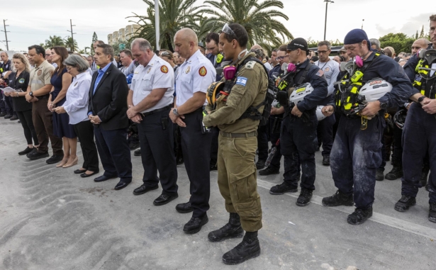 Members of search and rescue teams gather for a moment of silence and prayer at the memorial for the victims in the collapsed 12-story Champlain Towers South condo building in Surfside, Fla., on July 7, 2021. (Jose A Iglesias/Pool/Getty Images)