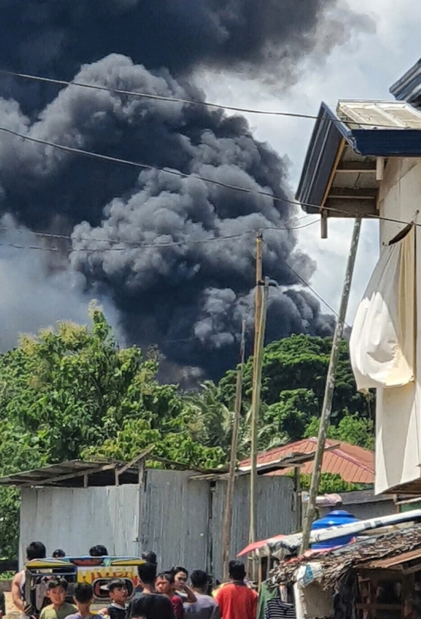 Residents gather as smoke rises from the wreckage, after a Philippine air force Lockheed C-130 transport plane, carrying troops, crashed on landing in Jolo, Sulu, Philippines, on July 4, 2021. (Bogs Muhajiran via Reuters)
