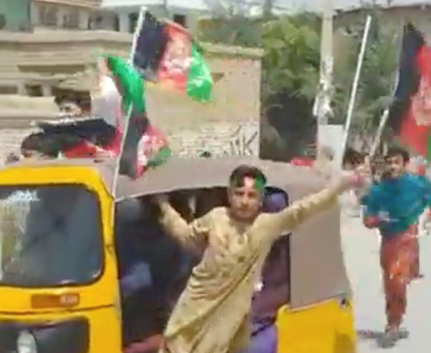 A man waves an Afghan flag as he rides an auto rickshaw along a street in Kabul, Afghanistan, in this still image taken from a video dated Aug. 19, 2021 (Obtained by Reuters)