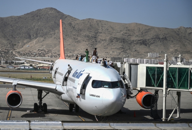 Afghan people climb atop a plane as they wait at the Kabul airport in Kabul on Aug. 16, 2021. (Wakil Kohsar/AFP via Getty Images)