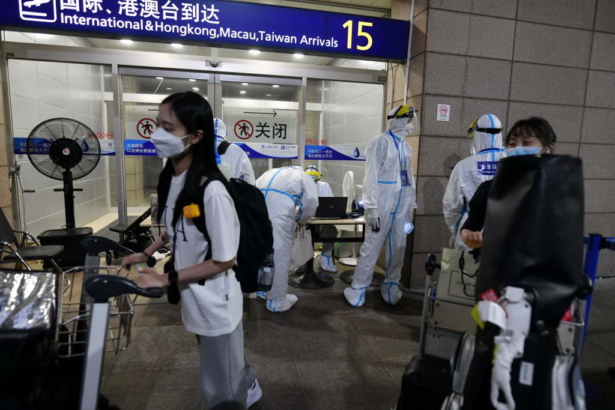 Workers in protective clothing as a precaution against the COVID-19 coronavirus help arriving international passengers as they prepare to board buses to be taken to quarantine hotels, at Pudong Airport in Shanghai, China, on Aug. 13, 2021. (Greg Baker/AFP via Getty Images)