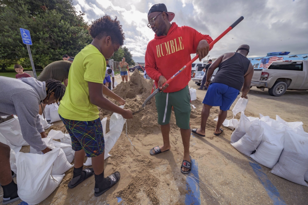 Jawan Williams shovels sand for a sandbag held by his son Jayden Williams, before landfall of Hurricane Ida at the Frederick Sigur Civic Center in Chalmette, La., which is part of the Greater New Orleans metropolitan area, on Aug. 28, 2021. (Matthew Hinton/AP Photo)