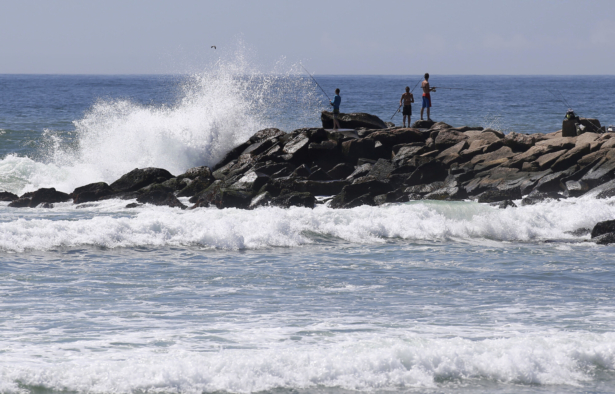 People fish as large waves hit the rocks at the Charlestown Breachway in Charlestown, R.I., on Aug. 21, 2021. (Stew Milne/AP Photo)