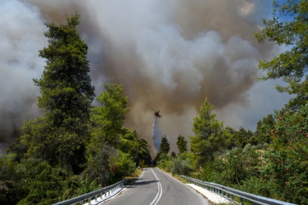 A firefighting helicopter makes a water drop as a wildfire burns near the village of Ellinika, on the island of Evia, Greece, on Aug. 8, 2021. (Alexandros Avramidis/Reuters)